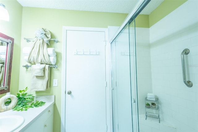 full bath featuring vanity, a shower stall, and a textured ceiling