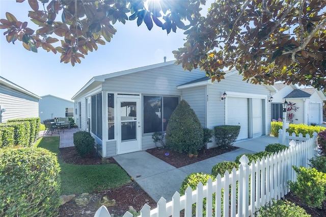 view of front facade featuring a fenced front yard, an attached garage, and a sunroom