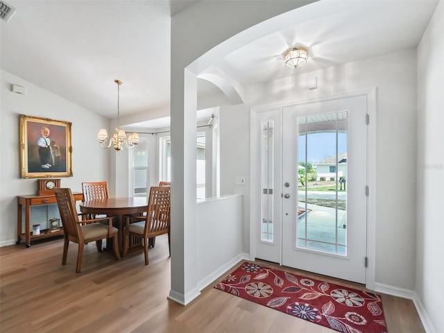 entrance foyer with an inviting chandelier, lofted ceiling, and wood-type flooring