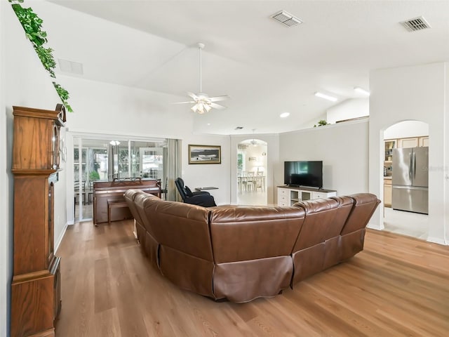 living room featuring ceiling fan, lofted ceiling, and light hardwood / wood-style flooring