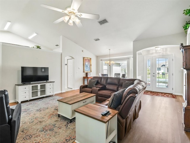 living room with lofted ceiling, dark wood-type flooring, and ceiling fan with notable chandelier