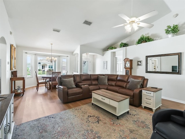 living room featuring hardwood / wood-style flooring, ceiling fan with notable chandelier, and vaulted ceiling