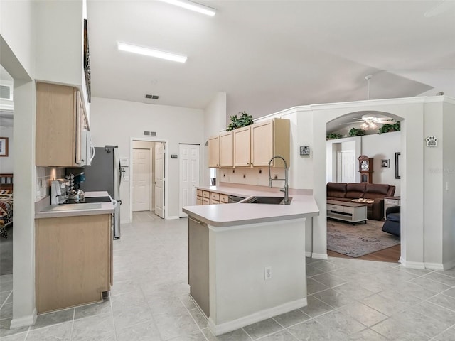 kitchen with lofted ceiling, sink, ceiling fan, kitchen peninsula, and light brown cabinets