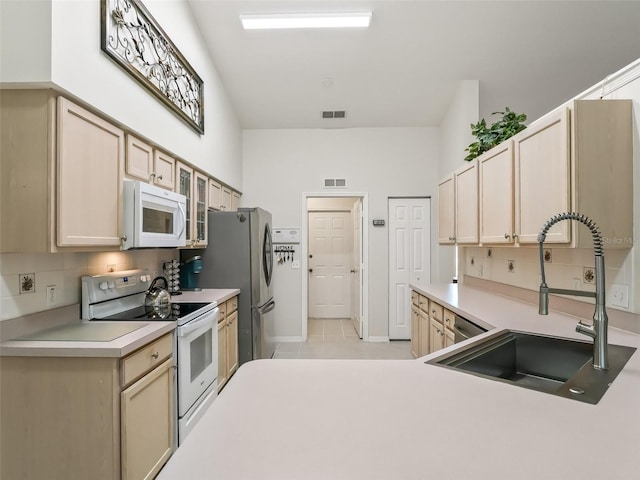 kitchen with white appliances, sink, decorative backsplash, and light brown cabinets