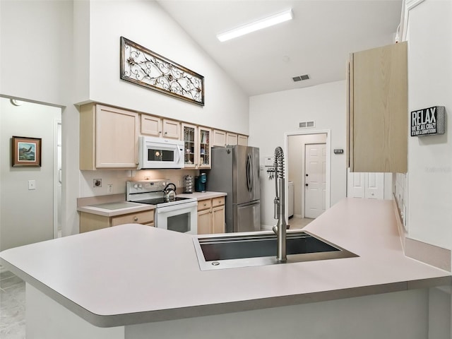 kitchen featuring sink, white appliances, kitchen peninsula, and a high ceiling