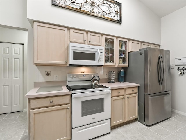 kitchen with light brown cabinets, backsplash, white appliances, and light tile patterned floors