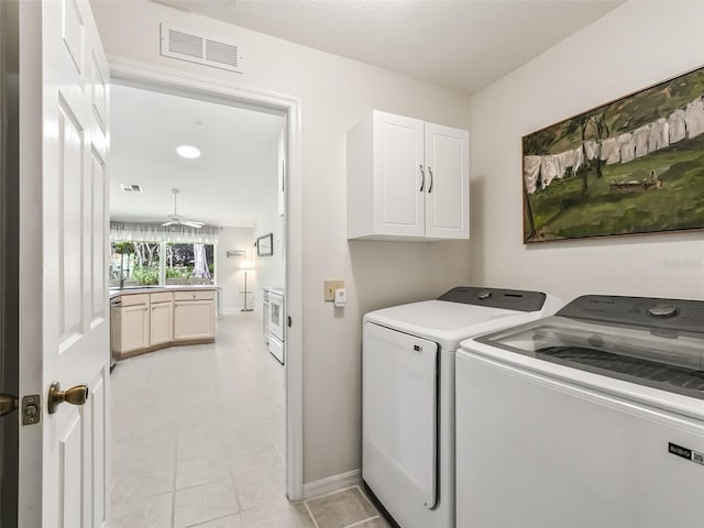 laundry room with ceiling fan, cabinets, separate washer and dryer, and light tile patterned floors