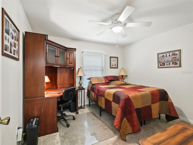 bedroom featuring ceiling fan, light colored carpet, and built in desk