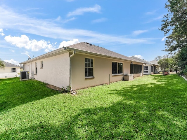 back of house with central AC unit and a lawn