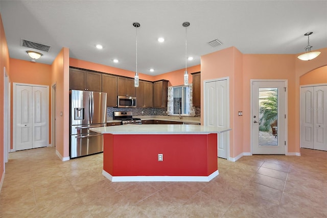 kitchen with dark brown cabinetry, decorative light fixtures, a kitchen island, stainless steel appliances, and backsplash