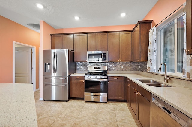 kitchen featuring tasteful backsplash, sink, light tile patterned floors, light stone counters, and stainless steel appliances