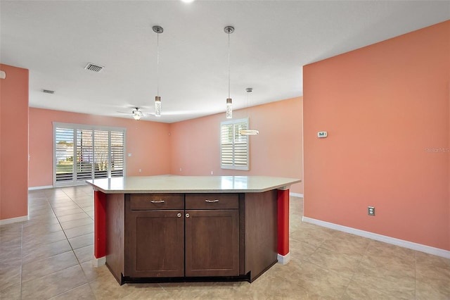 kitchen with dark brown cabinetry, hanging light fixtures, light tile patterned floors, and a center island