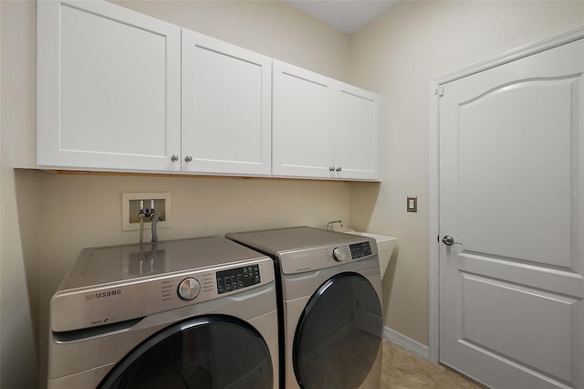 laundry room with cabinets, washing machine and dryer, and light tile patterned floors