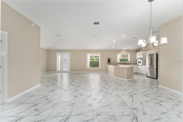 kitchen with appliances with stainless steel finishes, pendant lighting, sink, white cabinets, and an inviting chandelier