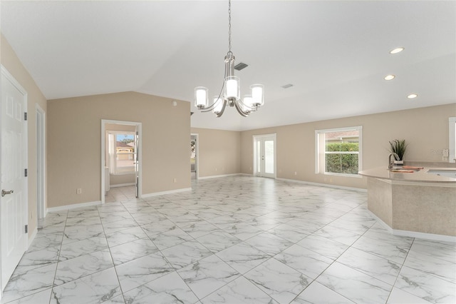 unfurnished living room featuring vaulted ceiling, a chandelier, and sink