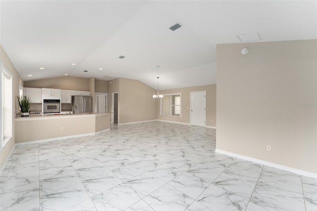 unfurnished living room featuring lofted ceiling, a healthy amount of sunlight, and a notable chandelier