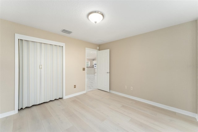 unfurnished bedroom featuring a closet, a textured ceiling, and light wood-type flooring