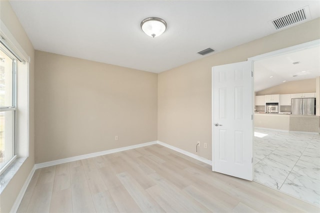 unfurnished room with lofted ceiling, a healthy amount of sunlight, and light wood-type flooring