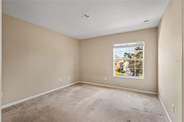 empty room with light colored carpet and a textured ceiling