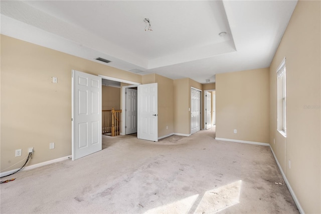 unfurnished bedroom featuring light carpet and a tray ceiling