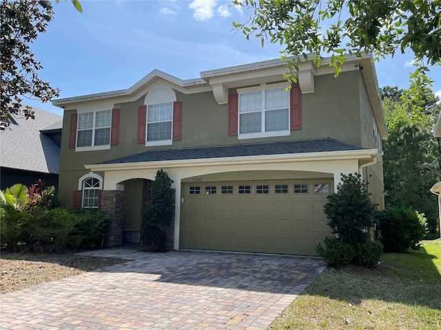 traditional-style home featuring stucco siding, decorative driveway, and an attached garage