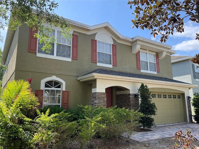 traditional home featuring a garage, stucco siding, driveway, and stone siding