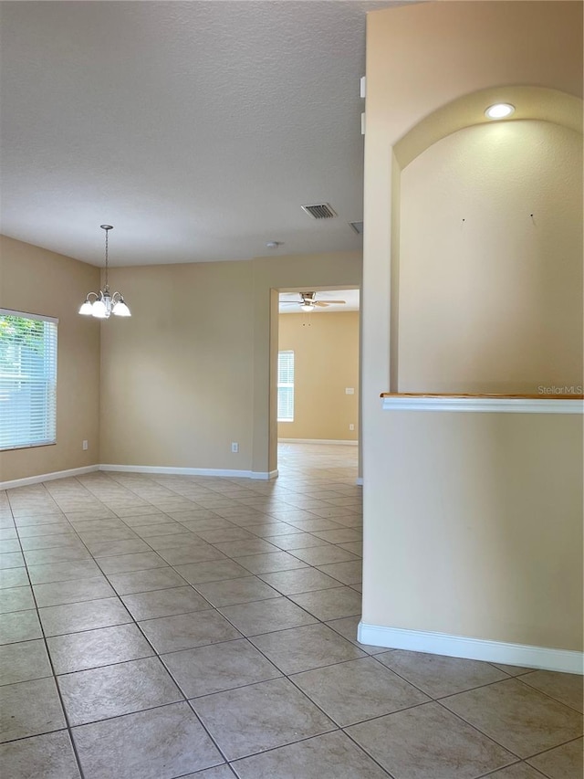 spare room with light tile patterned flooring, visible vents, a healthy amount of sunlight, and baseboards