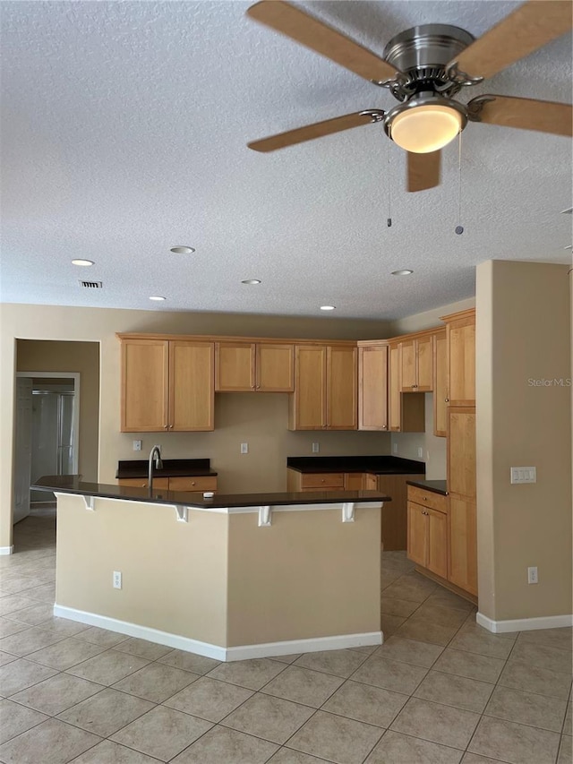 kitchen with a ceiling fan, light tile patterned floors, dark countertops, and a textured ceiling