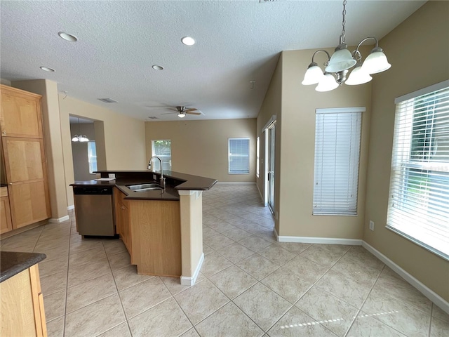 kitchen featuring a sink, a wealth of natural light, stainless steel dishwasher, dark countertops, and a textured ceiling
