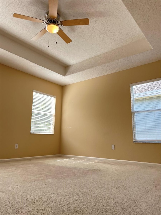 unfurnished room with a wealth of natural light, carpet flooring, and a textured ceiling