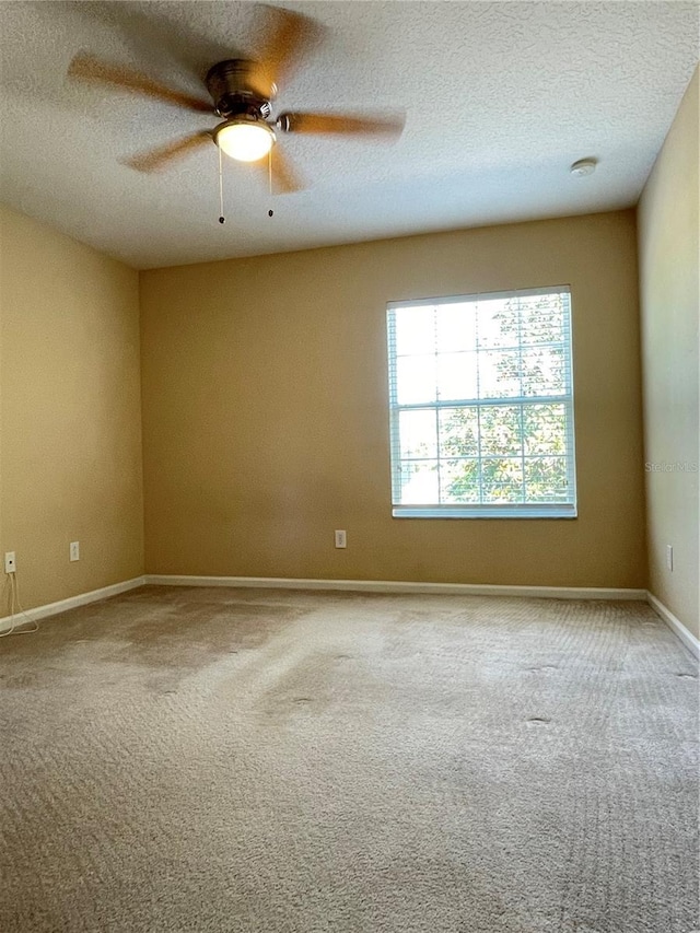 carpeted empty room featuring a textured ceiling, a ceiling fan, and baseboards