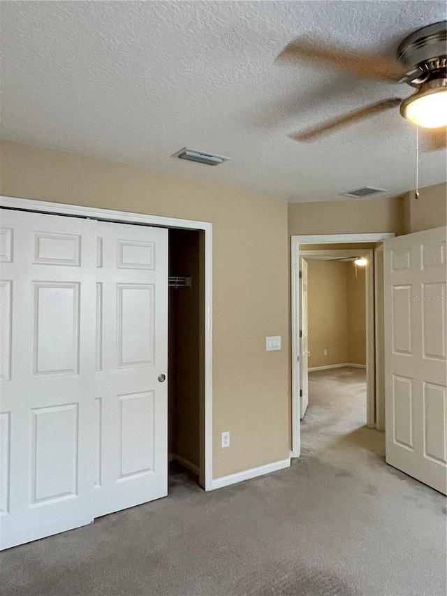 unfurnished bedroom featuring a closet, light carpet, and a textured ceiling