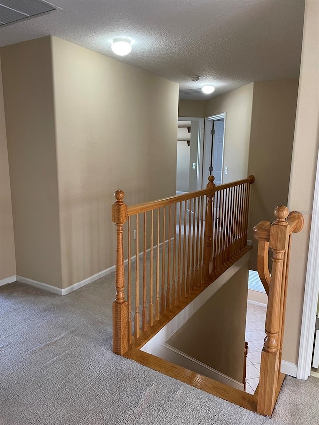 stairs featuring baseboards, visible vents, a textured ceiling, and carpet floors