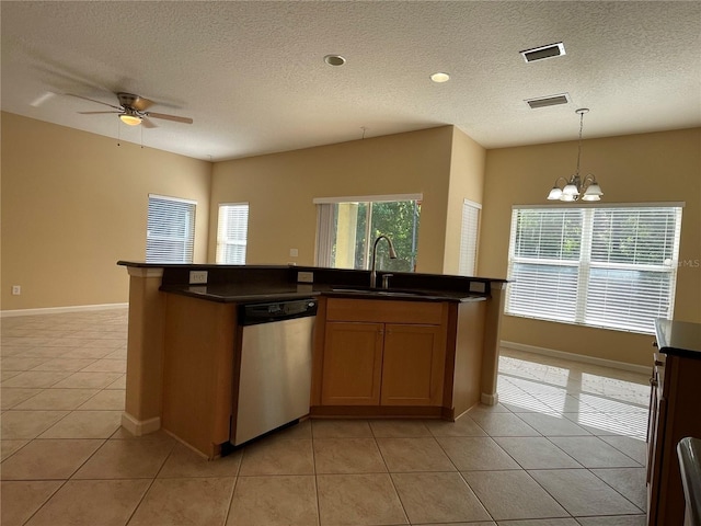 kitchen with dark countertops, stainless steel dishwasher, visible vents, and a sink