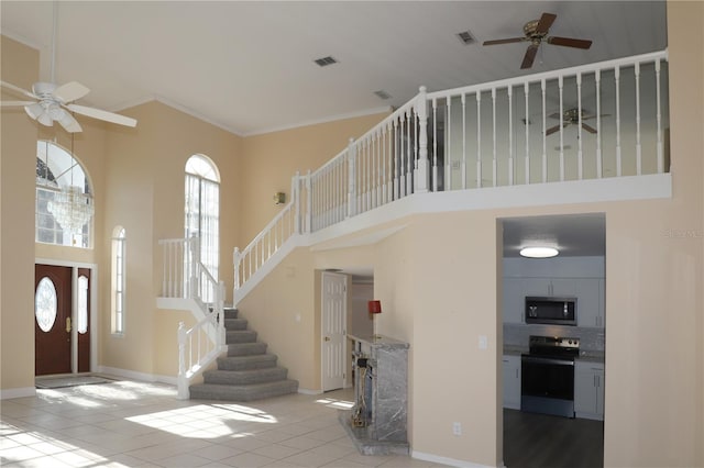 tiled entrance foyer with crown molding, a towering ceiling, and ceiling fan