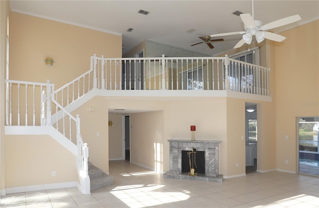 unfurnished living room with ornamental molding, a fireplace, light tile patterned floors, and a high ceiling