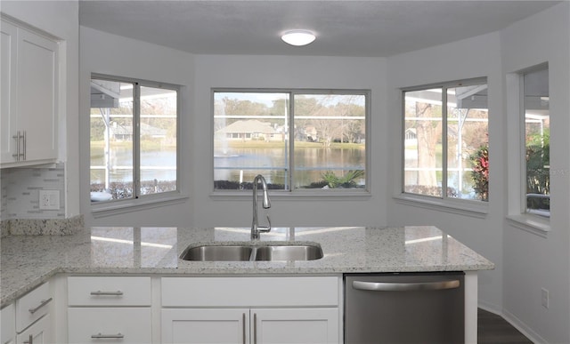 kitchen with white cabinetry, dishwasher, sink, and light stone counters