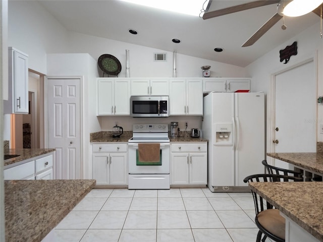 kitchen featuring white cabinetry, lofted ceiling, white appliances, and dark stone counters