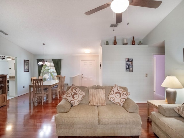 living room featuring dark hardwood / wood-style flooring, ceiling fan with notable chandelier, and vaulted ceiling