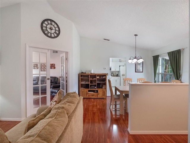 living room featuring wood-type flooring, vaulted ceiling, a textured ceiling, and a notable chandelier