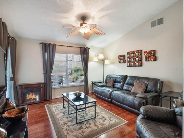 living room with lofted ceiling, a textured ceiling, dark wood-type flooring, and ceiling fan