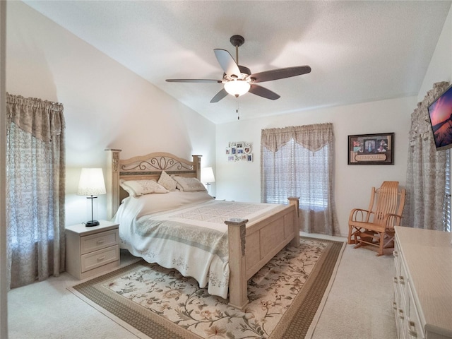 bedroom with ceiling fan, lofted ceiling, light carpet, and a textured ceiling