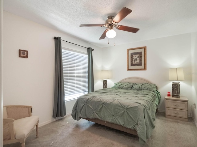 carpeted bedroom featuring ceiling fan and a textured ceiling