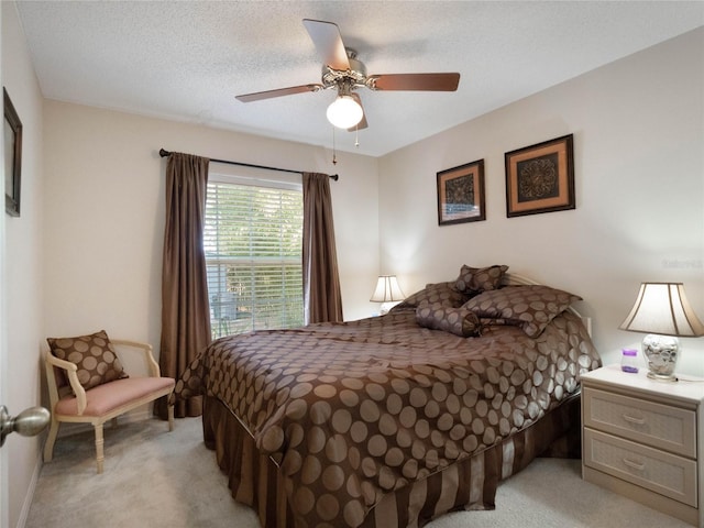 bedroom with ceiling fan, light colored carpet, and a textured ceiling