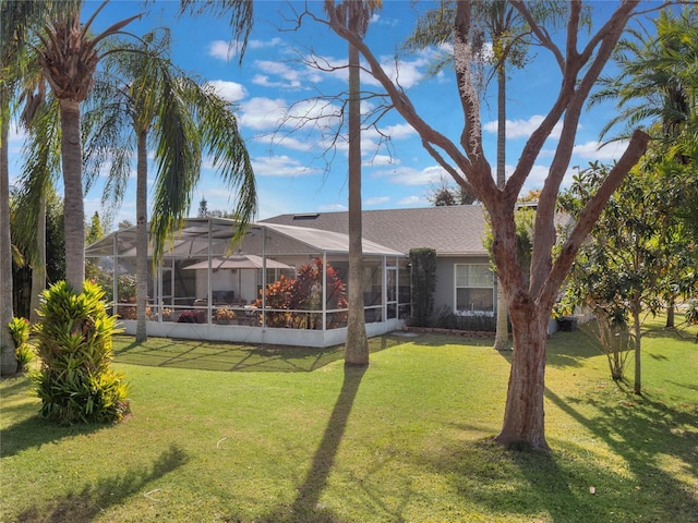 back of house with a lanai and a lawn