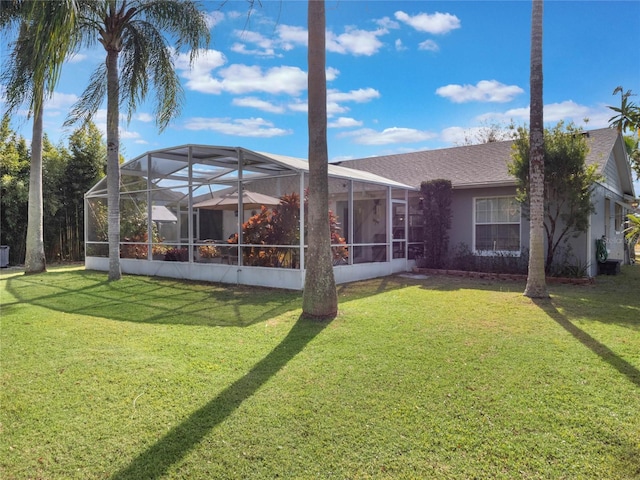 back of property with a yard and glass enclosure