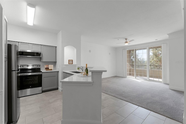 kitchen featuring sink, light carpet, appliances with stainless steel finishes, gray cabinets, and kitchen peninsula