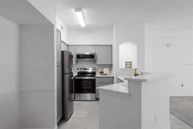 kitchen featuring light tile patterned flooring, sink, gray cabinetry, kitchen peninsula, and stainless steel appliances