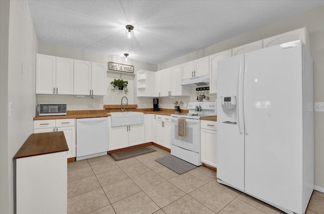 kitchen with sink, white appliances, light tile patterned floors, white cabinets, and wood counters