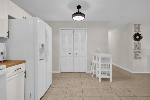 kitchen with white cabinetry, light tile patterned floors, and white refrigerator with ice dispenser